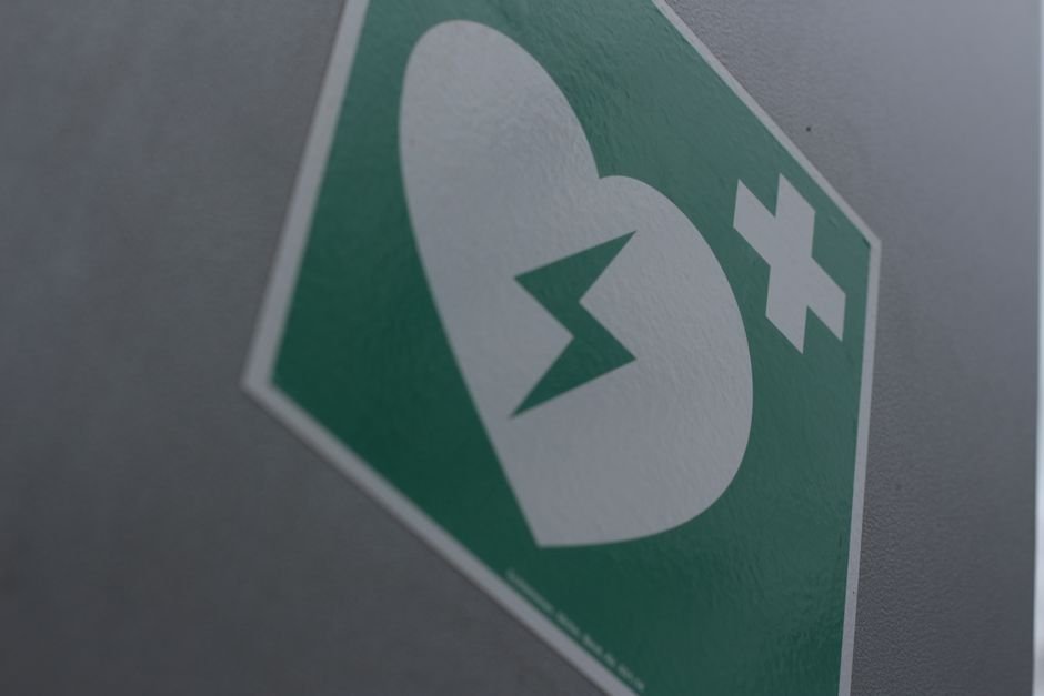 Señal verde de primeros auxilios con un corazón roto y símbolo de cruz para la concienciación sobre emergencias médicas.