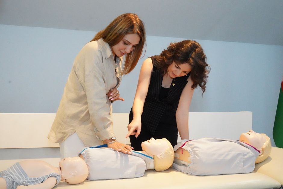 Dos mujeres demuestran técnicas de RCP en maniquíes durante una sesión de capacitación en interiores.