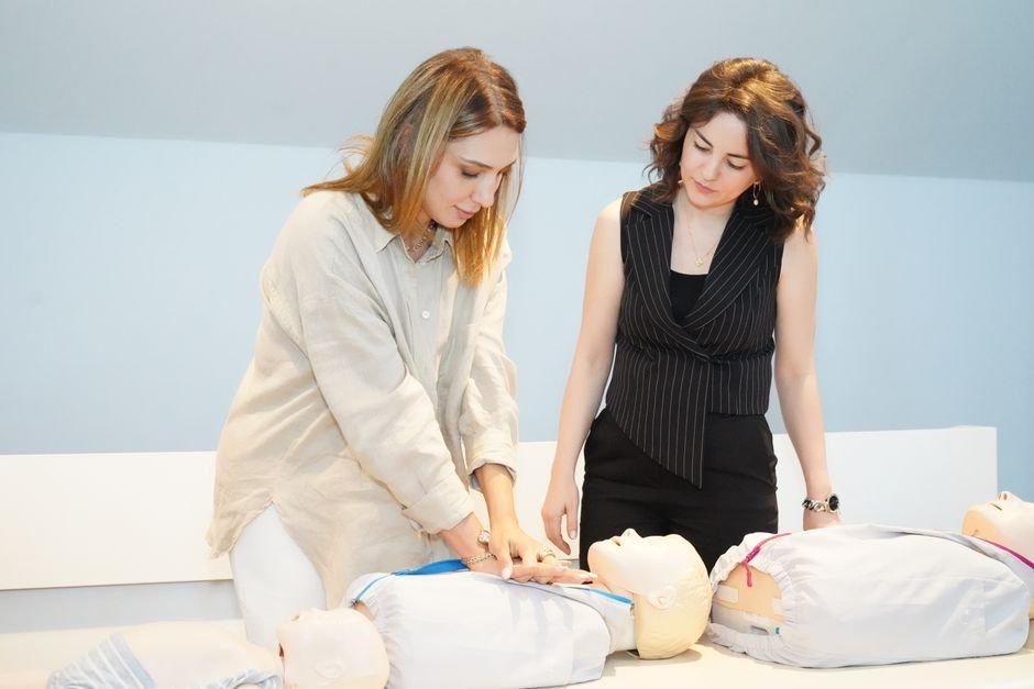 Dos mujeres aprendiendo técnicas de RCP en maniquíes de entrenamiento durante un taller de atención médica.